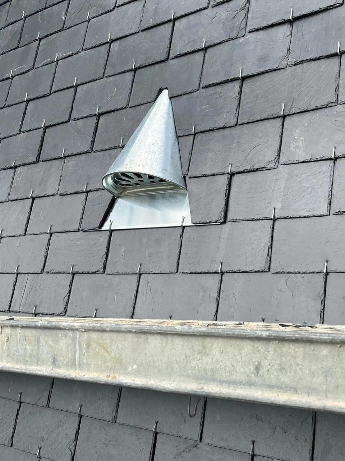Chatière de ventilation en zinc posée dans une couverture en ardoise