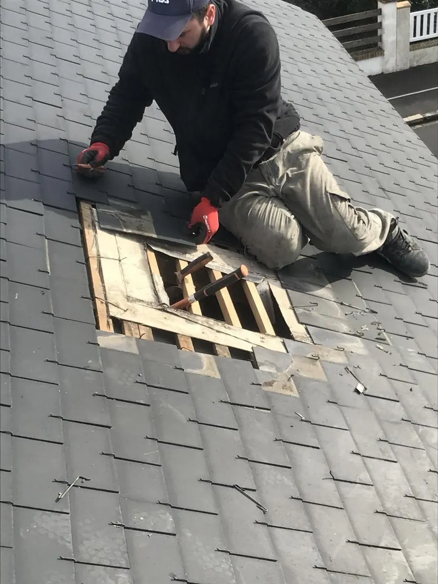Couvreur de Falck Rénovation ouvrant une zone d’ardoises pour réparer le support