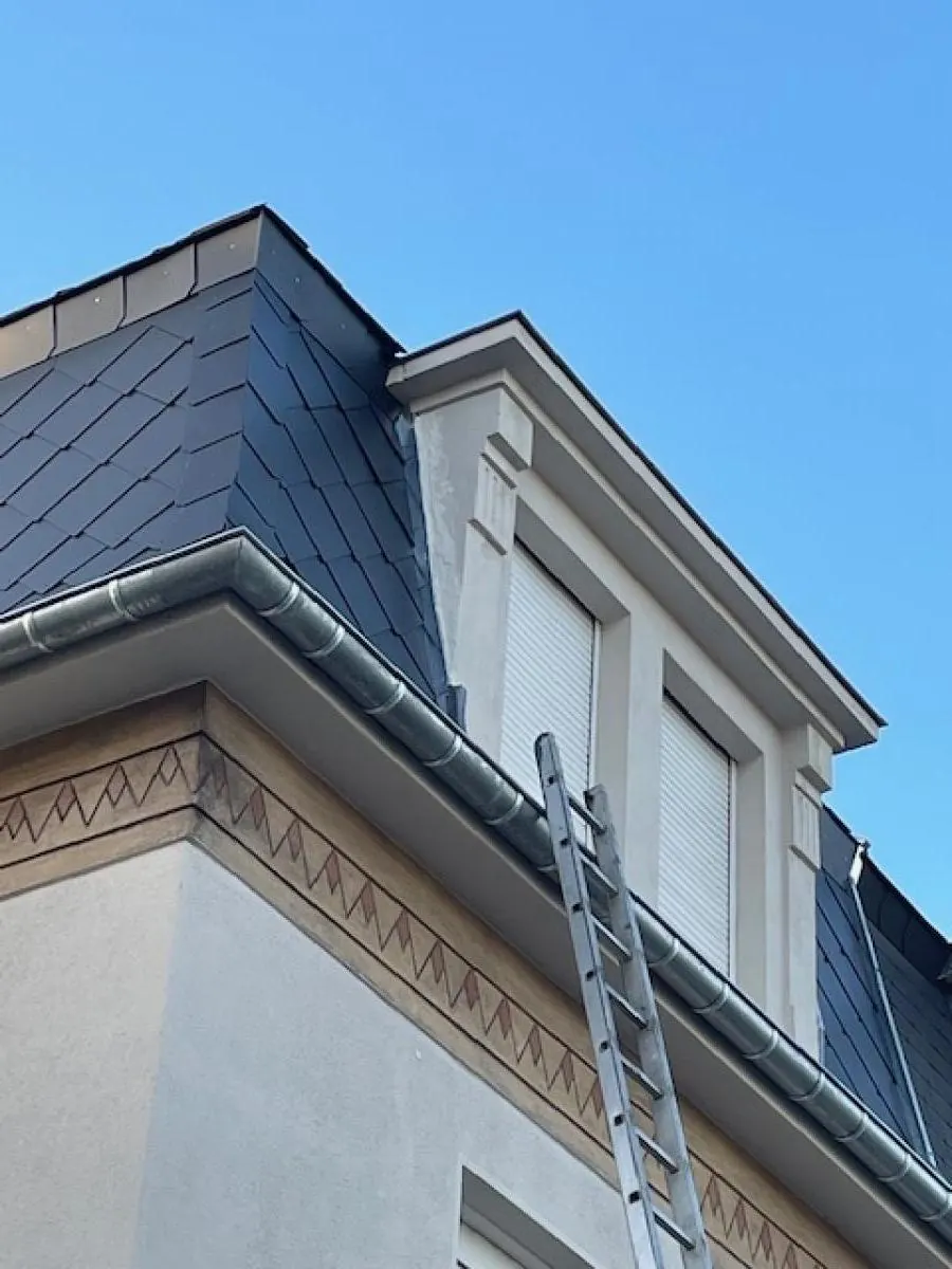 Lucarne habillée d’ardoise avec gouttière en zinc, échelle posée
