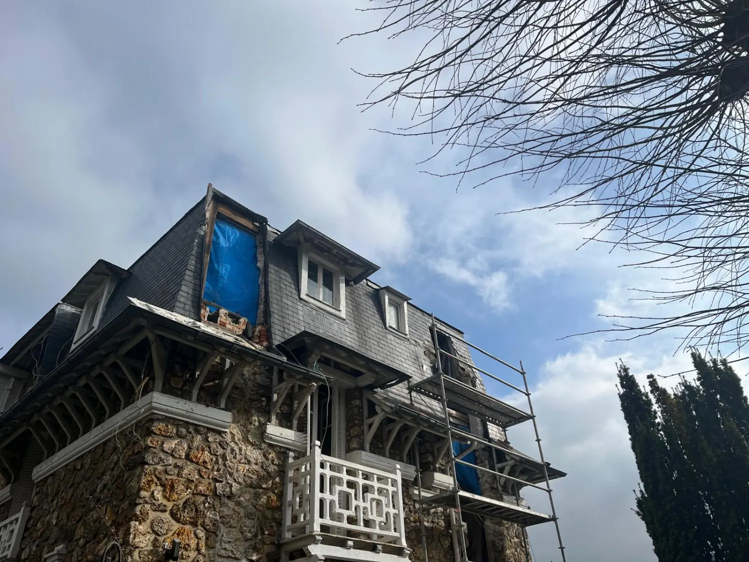 Maison à toiture en ardoise bâchée pendant les travaux, échafaudage monté