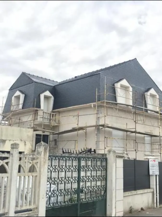 Maison à toiture en ardoise avec échafaudage monté en façade