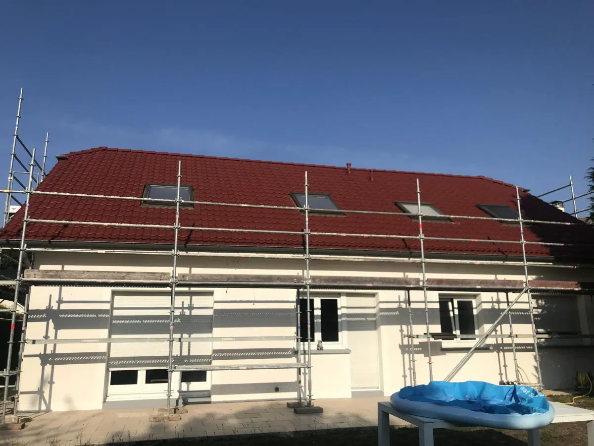 Toiture en tuiles rouges refaite, échafaudage encore monté le long de la façade